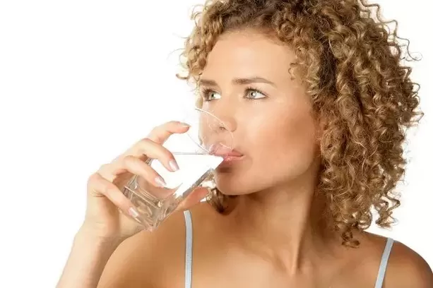 Dievča dodržiava diétu pre lenivých, pred jedlom vypije pohár vody